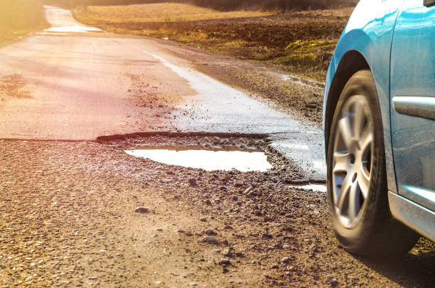 Car and winter pothole on open road stock photo