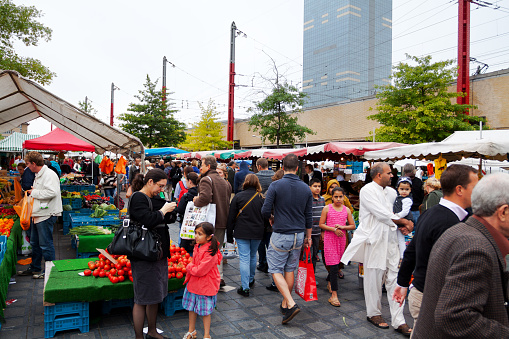 Many people on multi-ethnic weekend market in Brussels at station Midi. Market is around station and on both sides. In scene are people different ethnicities.
