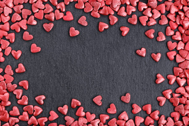 istock Red heart shaped sprinkles on black background 1143013519