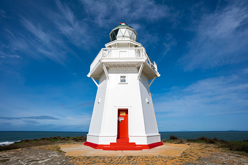 Lighthouse with red door on a blue sky background