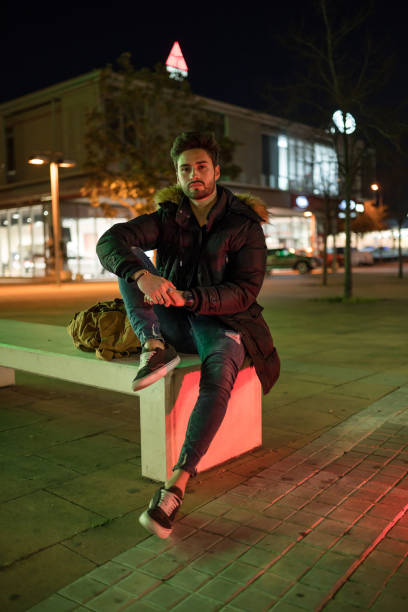 istock Stylish young man sitting on a street bench 1143017308