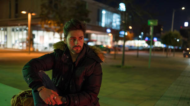 istock Stylish young man sitting on a street bench 1143019138