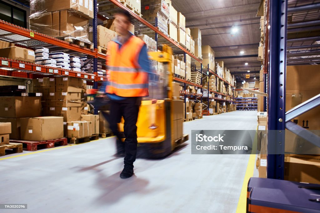 Warehouse, worker with a forklift in motion blur. Warehouse Stock Photo