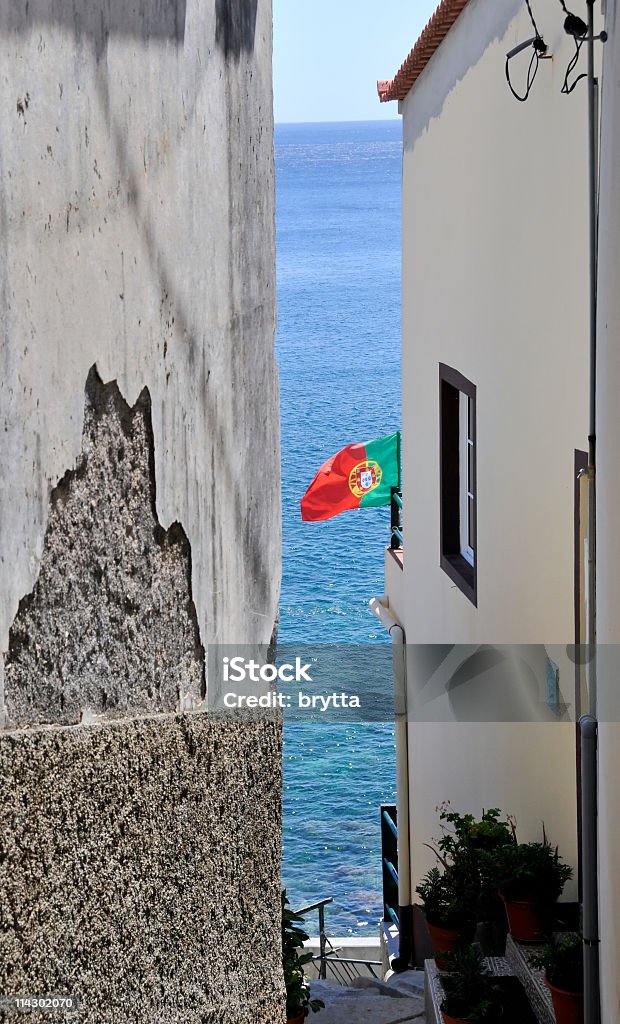 Narrow alley leading to ocean,Madeira Island Narrow alley with Portuguese flag leading to the ocean,Madeira Island. Alley Stock Photo