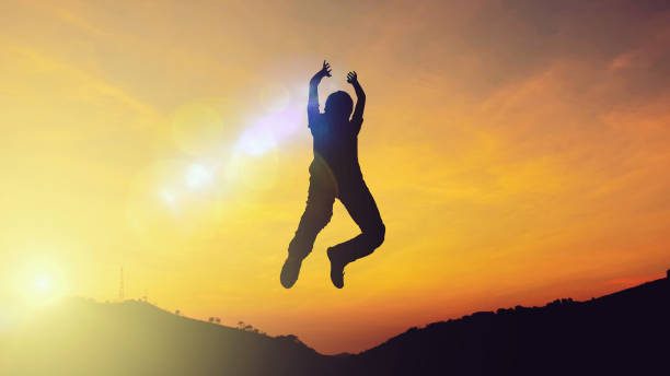 istock Silhouette of a young man jumping on background with sunset. front view 1143028010