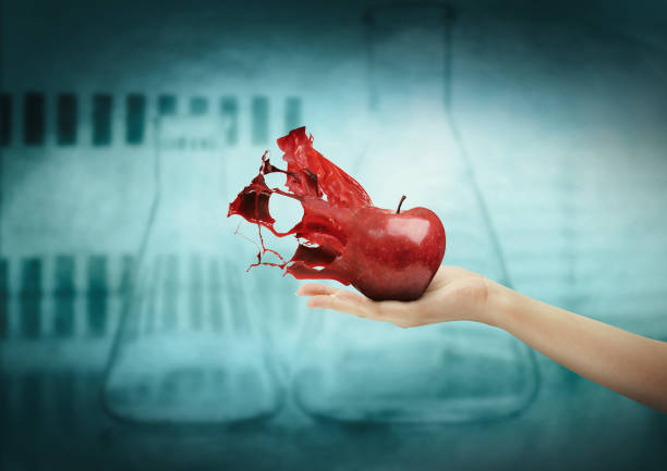 Hand holding apple disintegrating through splashs. Front view
