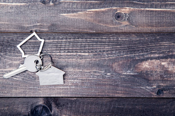 istock Silver key with house symbol on brown wooden table 1143029759