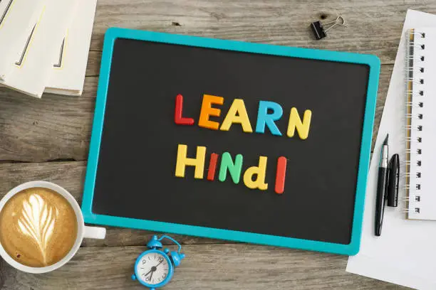 Photo of Dark chalkboard with Learn Hindi message from colourful plastic letters