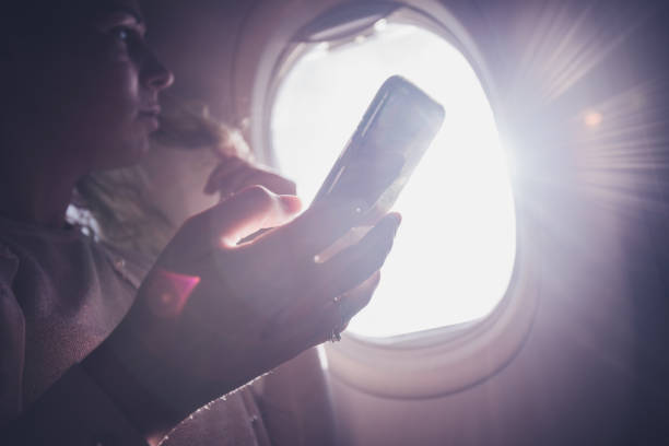 istock Young woman holding mobile and looking in view from airplane. 1143031302