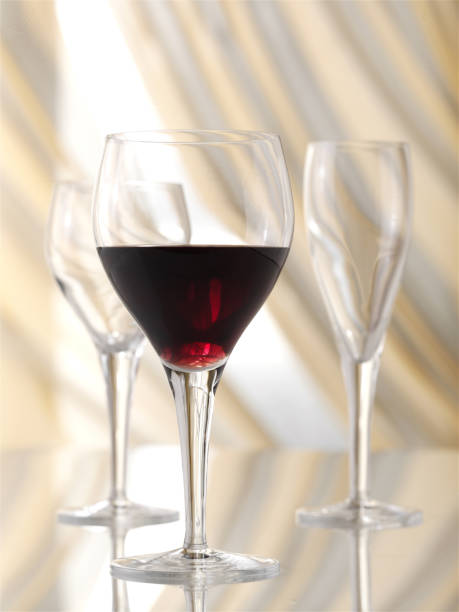 istock One glass of red wine and two empty wine glasses on the table. 1143033678