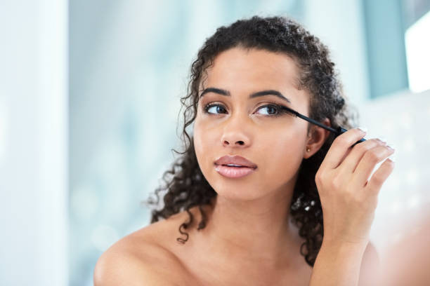 The longer the lashes, the better! Shot of a beautiful young woman applying mascara in her bathroom mirror mascara wands stock pictures, royalty-free photos & images