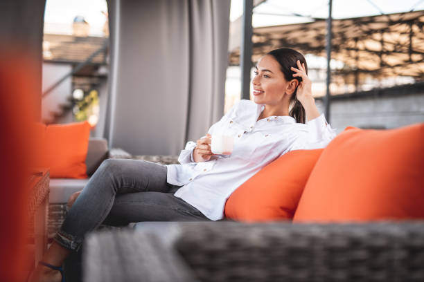istock Smiling lady relaxing on the couch and drinking coffee 1143036375
