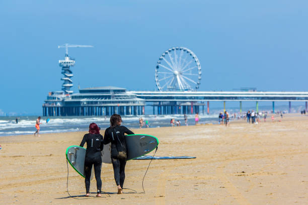 scheveningen, the Netherlands - June 27 2018: Scheveningen pier with beach and young people with surf boards