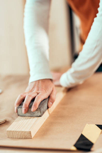 istock Female carpenter manually sanding wooden plank 1143037941
