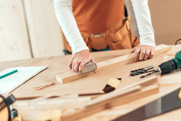 istock Female carpenter manually sanding wooden plank 1143038134