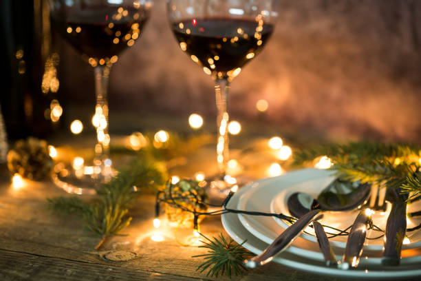 istock Closeup of red wine on table with Christmas lights. Christmas table and tree. 1143040954