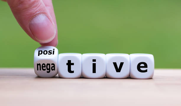 Hand turns a dice and changes the expression "negative" to "positive". Hand turns a dice and changes the expression "negative" to "positive". negative emotion stock pictures, royalty-free photos & images