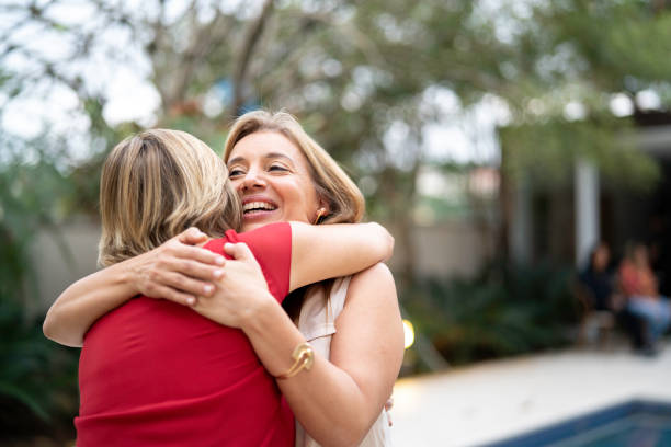 Mother and daughter embracing in front o house