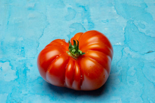istock Brandywine red tomatoes, in heart shape on grunge blue background 1143044559