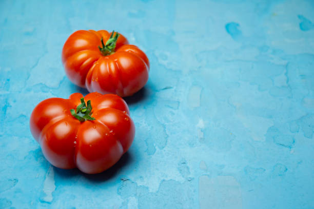 istock Beautiful Brandywine red tomatoes on grunge blue background with blank space 1143044563