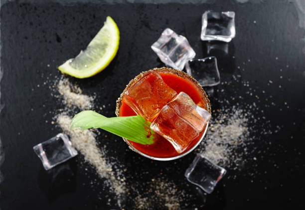 Bloody Mary with tomatoes, rosemary and chili peppers on a black background, alcoholic cocktail with tomato juice, close up.