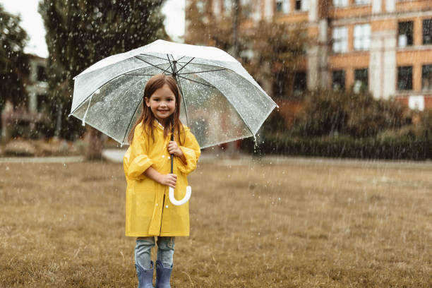 istock Small girl standing outside and hiding from rain 1143045667