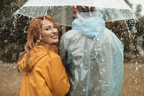 istock Delighted couple walking together in rain 1143045769