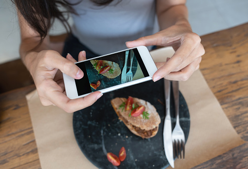 Close-up on a woman taking a picture of her food at a restaurant for social media - lifestyle concepts