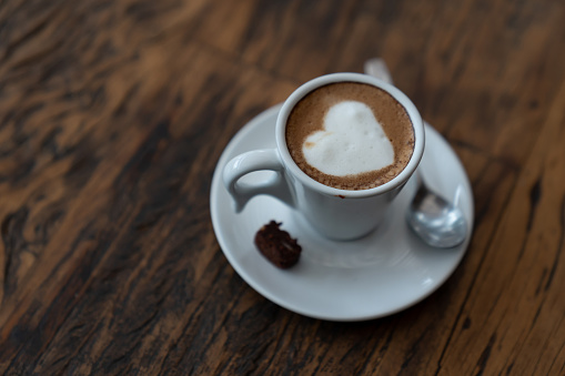 Cup of coffee with a heart on a gray background. Valentine's Day. Top view, selective focus