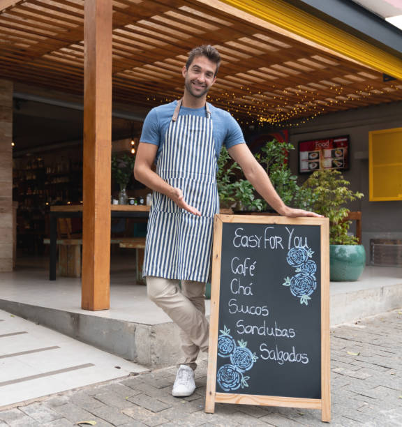 istock Friendly business owner pointing at the menu board at his restaurant 1143046147