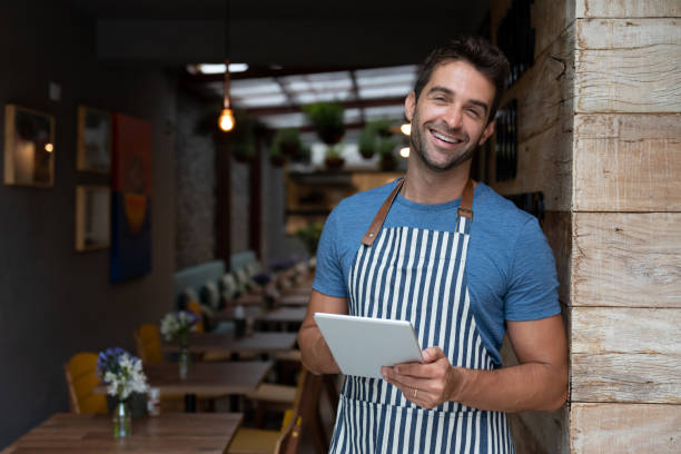 istock Happy business owner working at a cafe using a digital tablet 1143046165