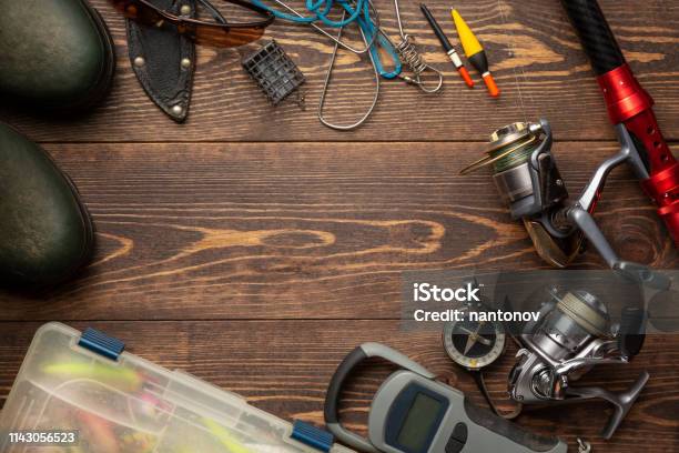 Fishing Theme Frame With Rubber Boots Fishing Box Reels Fishing Buoy Rod Compass Feeder Knife And Fish String On Wooden Background Free Space Stock Photo - Download Image Now