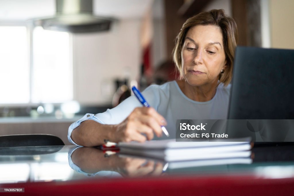 Mature woman working at home Mature woman doing homeoffice Learning Stock Photo