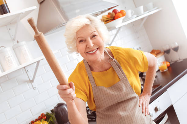 istock Old woman laughs but threatens with rolling pin at camera 1143057989
