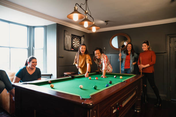 Playing Eight Ball Small group of friends playing pool in a games room in a house. college dorm party stock pictures, royalty-free photos & images