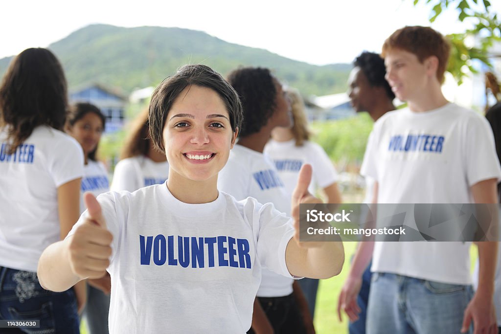 Volontariato felice ragazza mostrando pollice in alto - Foto stock royalty-free di Volontario