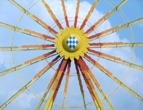 frontal detail of a multicolored big wheel with big cloud and little blue sky in the back