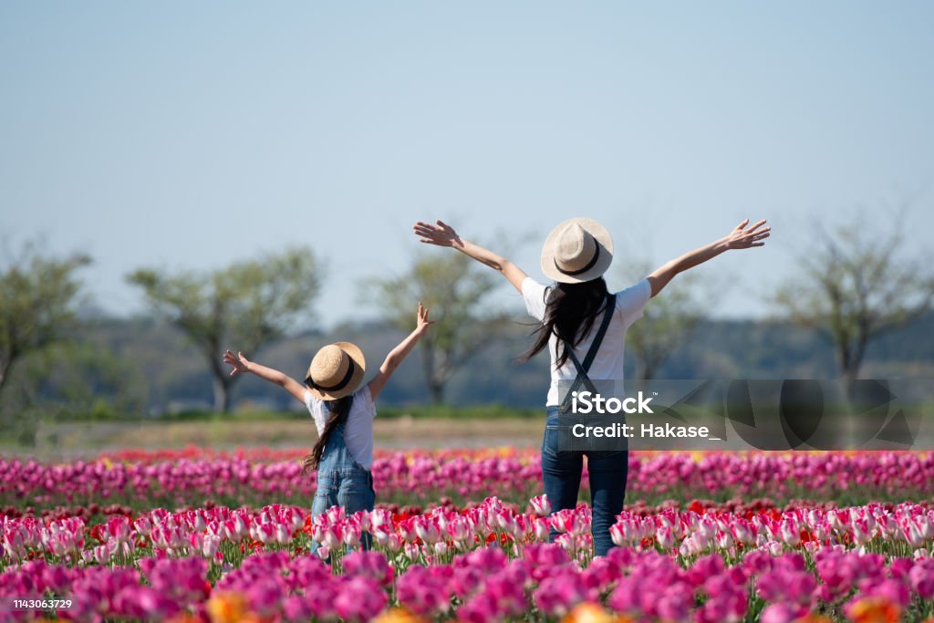 花の畑で手を上げている母子 - 春のロイヤリティフリーストックフォト