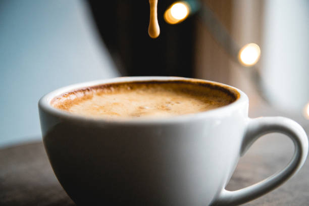 istock Drop of coffee froth from a spoon in a white cup. Blue and lightly background. 1143064150