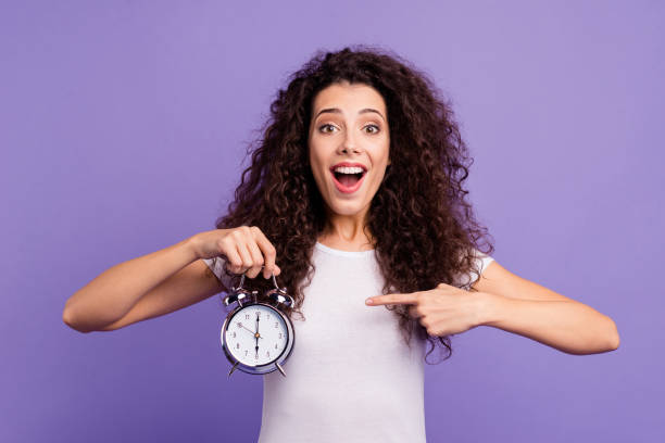 portrait of her she nice cute charming attractive cheerful cheery brunette wavy-haired lady showing forefinger clock isolated on bright vivid shine violet purple background - clock face fotos imagens e fotografias de stock