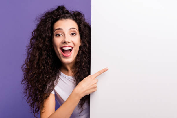 close-up portrait of her she nice cute attractive charming cheerful brunette wavy-haired lady showing forefinger aside big large ad advert isolated over bright vivid shine violet purple background - aside imagens e fotografias de stock