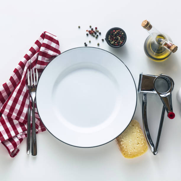 istock white enamelled empty plate on the table with a red checkered napkin and parmesan cheese with its grater. Typical Mediterranean style 1143064502