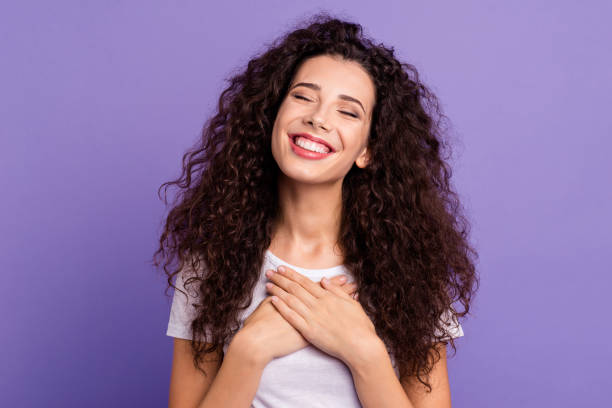 close up photo beautiful amazing her she lady eyes closed hold both arms hands on chest very pleased sweet emotions feelings wear casual white t-shirt clothes outfit isolated violet purple background - silence curly hair facial expression female imagens e fotografias de stock