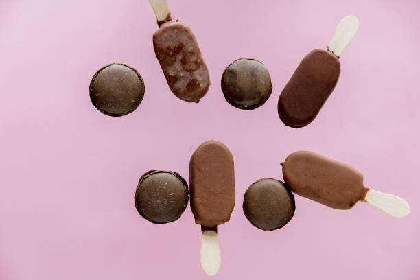 istock Chocolate ice lollys and french macrons on pink background. 1143067731