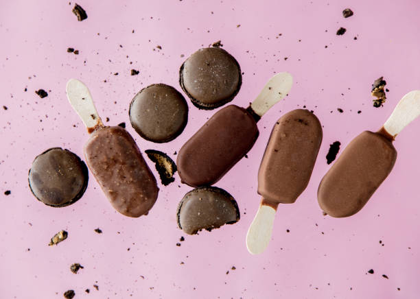 istock Chocolate ice lollys and french macrons on pink background. 1143067732