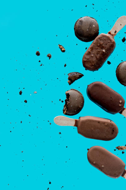 istock Chocolate ice lolly and french macrons on blue background. Objects without of a shadows 1143067844