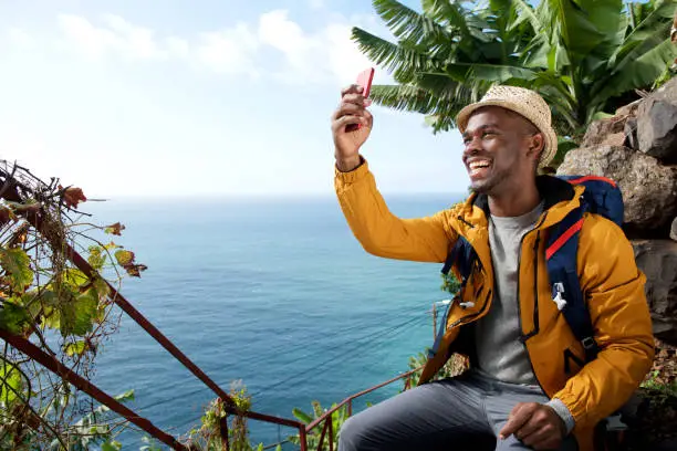 Photo of happy african american travel man taking selfie