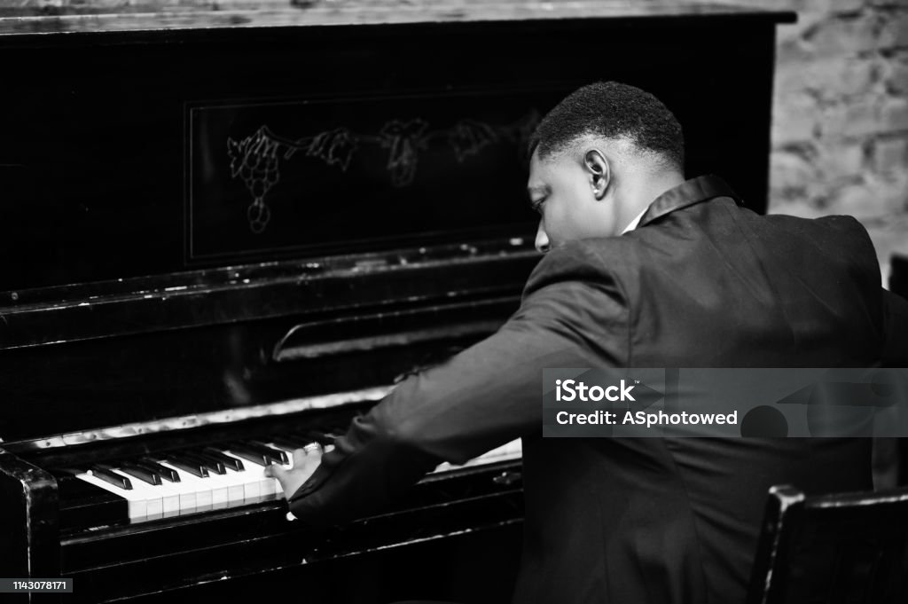 Strong powerful african american man in black suit Back of strong powerful african american man in black suit play piano. Jazz Music Stock Photo
