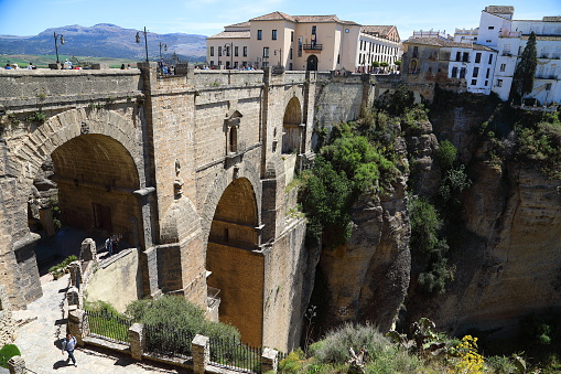 People at Puente Nuevo Bridge in Ronda Andalusia, Spain. The bridge was finished in 1751 after 52 years of construction. It bridges the aprox. 100 m. deep chasm between the old and new part of the city.