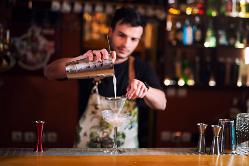 Man bartender pouring alcohol in glass, A young bartender making luxury cocktail.